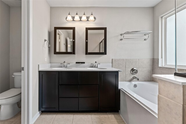 full bath featuring toilet, a sink, a bath, and tile patterned floors