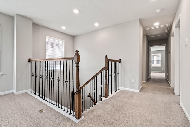 corridor with carpet, attic access, baseboards, and an upstairs landing