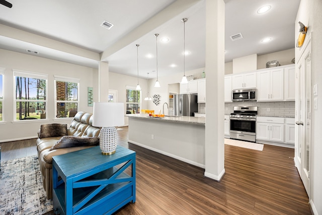 kitchen with open floor plan, appliances with stainless steel finishes, visible vents, and decorative backsplash