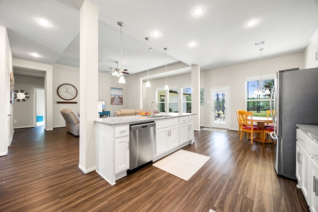 kitchen featuring dark wood-type flooring, light stone countertops, stainless steel appliances, white cabinetry, and a sink