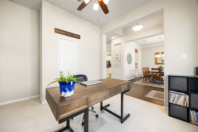 carpeted office featuring ceiling fan, ornamental molding, wood finished floors, and baseboards