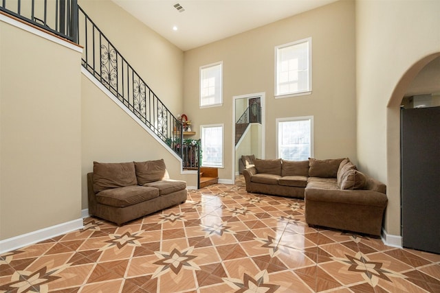 living area with stairway, visible vents, baseboards, and a wealth of natural light