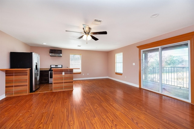 unfurnished living room featuring a ceiling fan, wood finished floors, visible vents, and baseboards