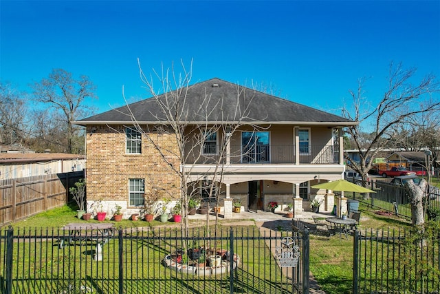 rear view of house featuring a yard, a balcony, a fenced backyard, and a patio area