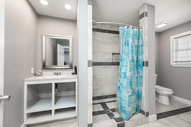 bathroom with vanity, toilet, baseboards, and a tile shower