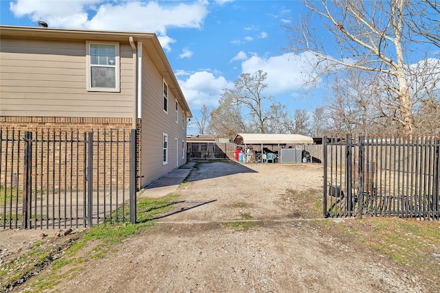 view of property exterior with brick siding, driveway, fence private yard, and a gate