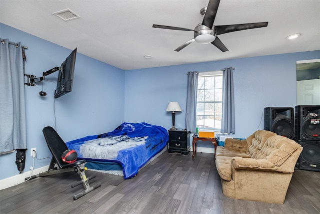 bedroom with ceiling fan, visible vents, baseboards, and wood finished floors