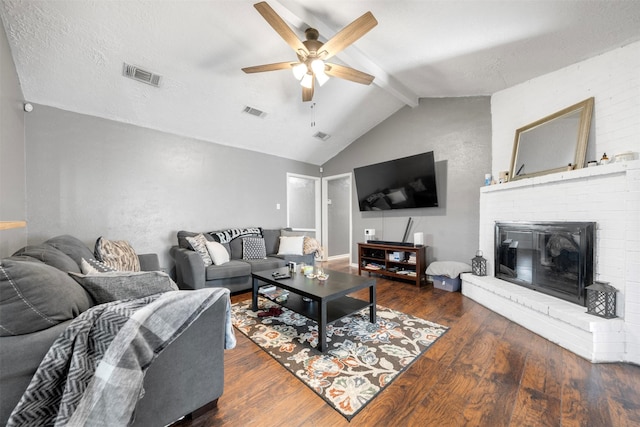 living room featuring lofted ceiling with beams, a fireplace, wood finished floors, and visible vents