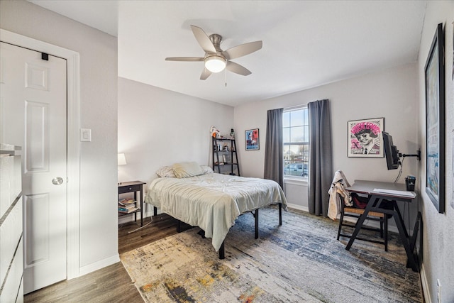 bedroom with ceiling fan, baseboards, and wood finished floors