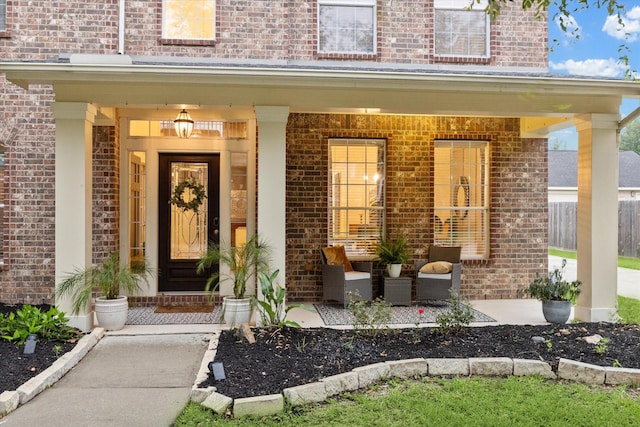 view of exterior entry with brick siding and a porch