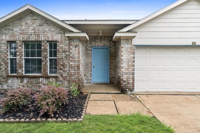 view of exterior entry with a garage and brick siding