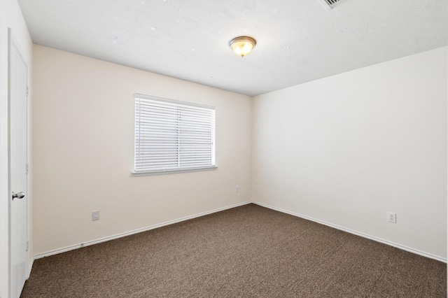 unfurnished room with dark colored carpet and baseboards