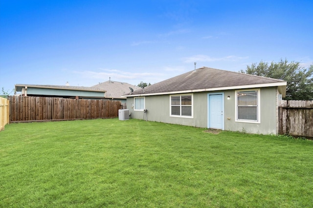 rear view of property featuring cooling unit, a fenced backyard, and a lawn