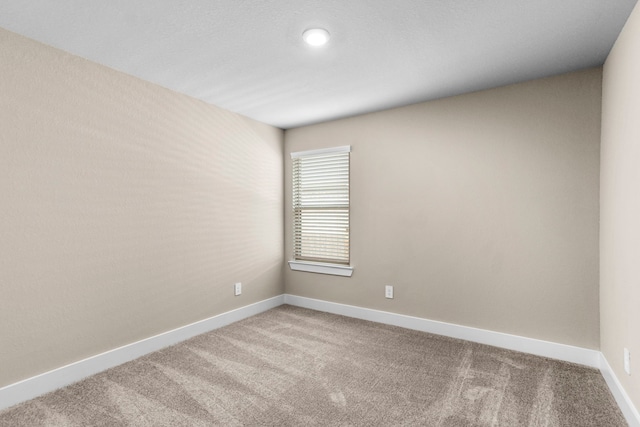 carpeted empty room featuring baseboards