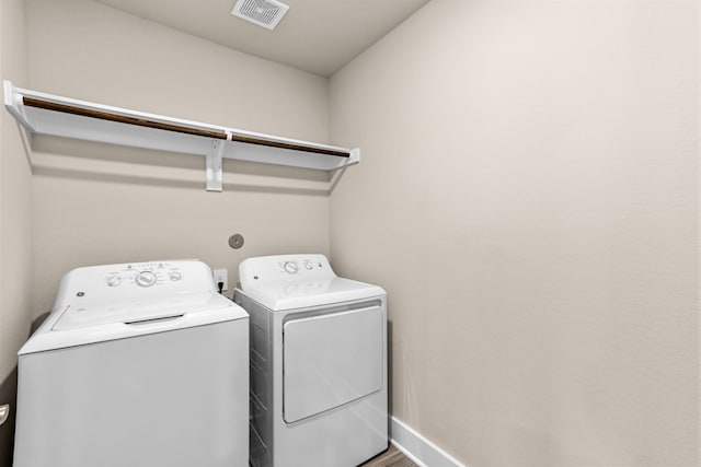 laundry room with laundry area, washing machine and dryer, visible vents, and baseboards