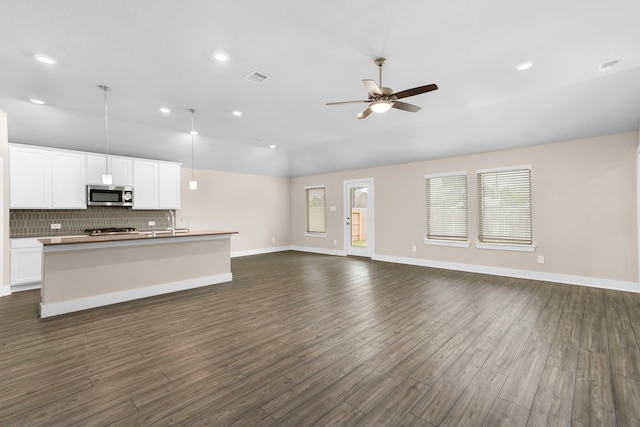 kitchen with open floor plan, stainless steel microwave, visible vents, and decorative backsplash