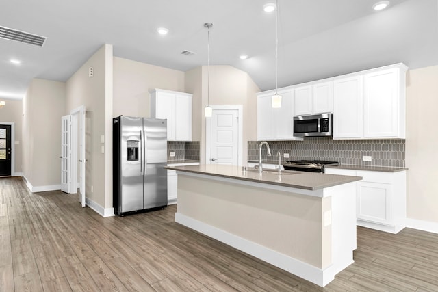 kitchen featuring light wood finished floors, visible vents, decorative backsplash, appliances with stainless steel finishes, and a sink