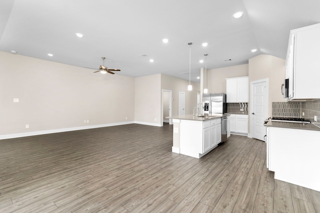 kitchen featuring a center island with sink, tasteful backsplash, appliances with stainless steel finishes, light wood-style floors, and open floor plan