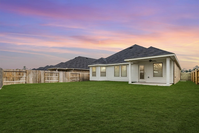 rear view of house featuring a patio, a fenced backyard, a ceiling fan, a yard, and roof with shingles