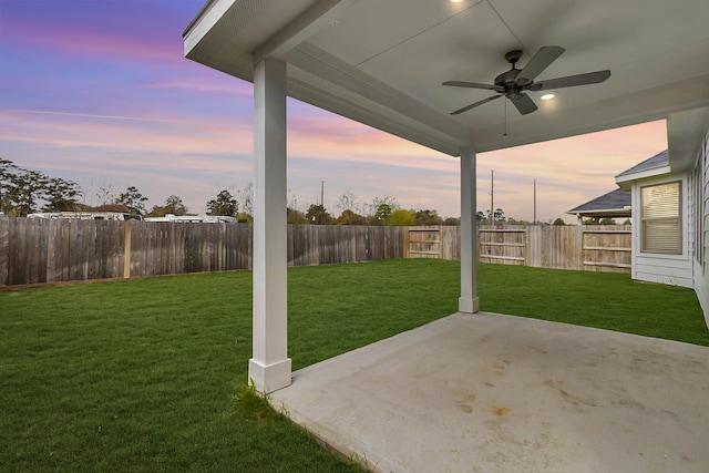 yard at dusk featuring a ceiling fan, a fenced backyard, and a patio