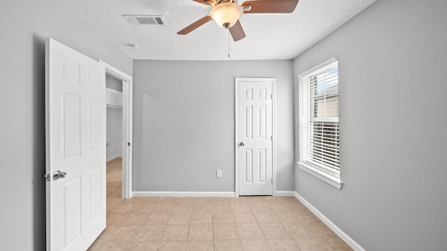 unfurnished bedroom featuring ceiling fan, light tile patterned flooring, visible vents, and baseboards