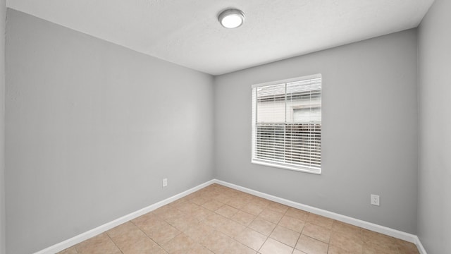 unfurnished room featuring light tile patterned floors, baseboards, and a textured ceiling