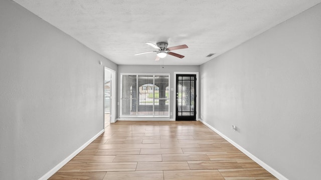 empty room featuring a textured ceiling, ceiling fan, and baseboards