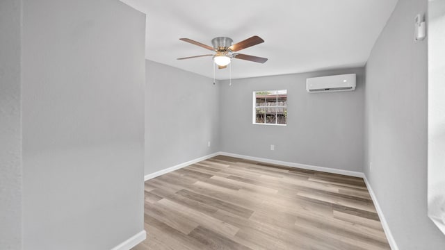 unfurnished room with an AC wall unit, baseboards, and wood finished floors