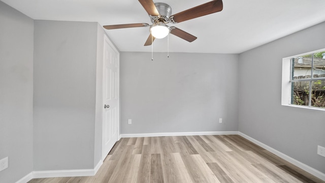 unfurnished room with ceiling fan, light wood finished floors, and baseboards