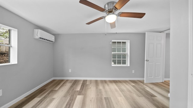 unfurnished room with ceiling fan, a wall mounted air conditioner, light wood-style flooring, and baseboards