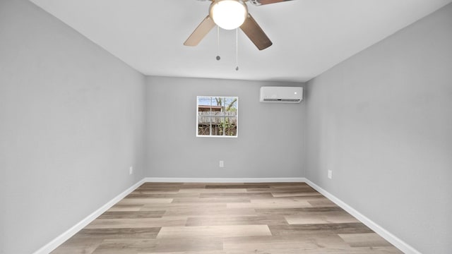 spare room featuring light wood-style floors, an AC wall unit, ceiling fan, and baseboards