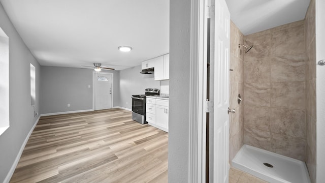 interior space with baseboards, light wood-style floors, stainless steel range with electric cooktop, under cabinet range hood, and white cabinetry