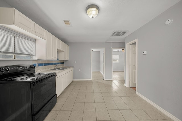 kitchen with light tile patterned floors, visible vents, black / electric stove, and white cabinets