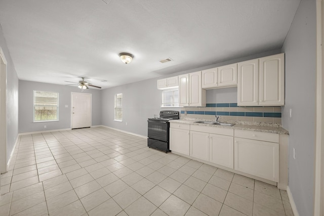 kitchen featuring black / electric stove, a sink, visible vents, white cabinets, and decorative backsplash