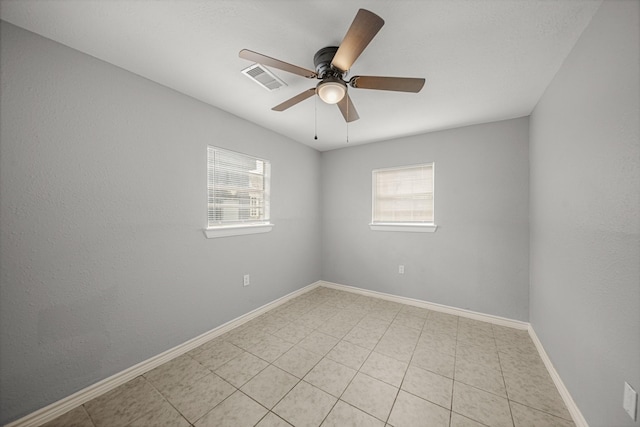 unfurnished room featuring ceiling fan, a wealth of natural light, visible vents, and baseboards