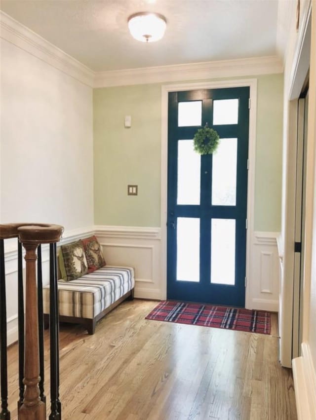 entrance foyer featuring ornamental molding, wood finished floors, and wainscoting