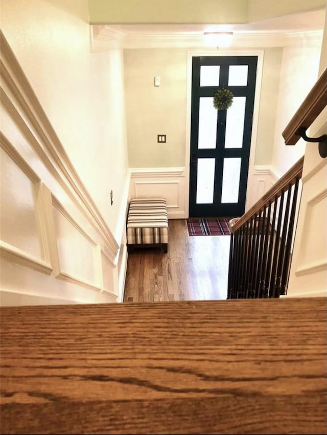 foyer with a wainscoted wall, stairway, wood finished floors, french doors, and a decorative wall