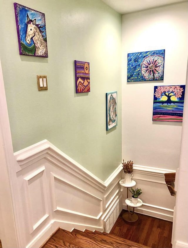 staircase featuring a wainscoted wall and wood finished floors