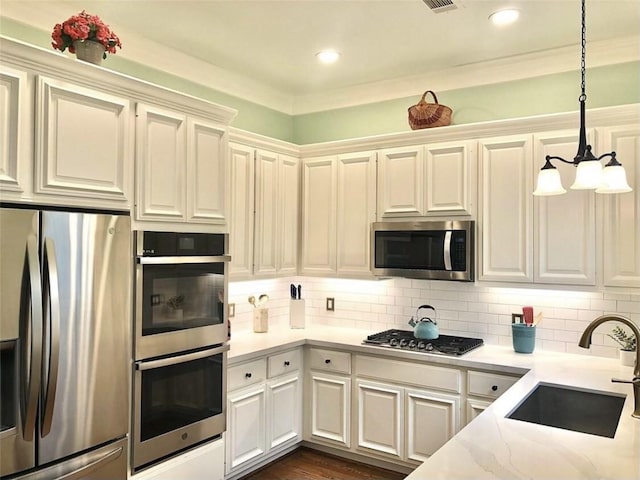 kitchen with decorative backsplash, appliances with stainless steel finishes, hanging light fixtures, a sink, and recessed lighting