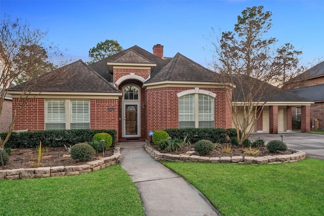 view of front of house with a garage, a front yard, concrete driveway, and brick siding