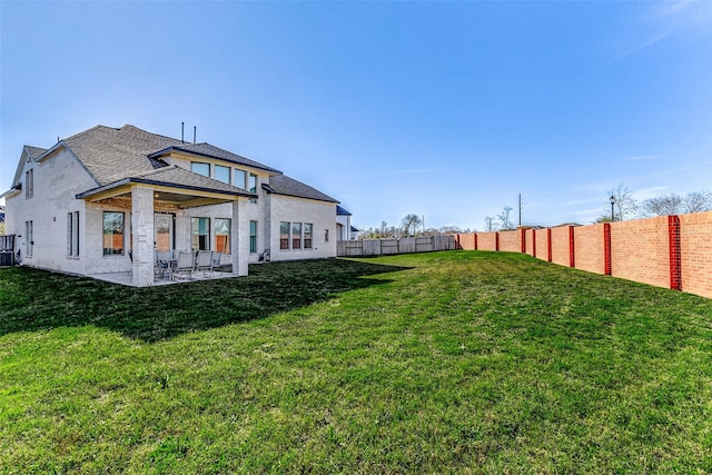 rear view of house with a yard, a patio area, and a fenced backyard