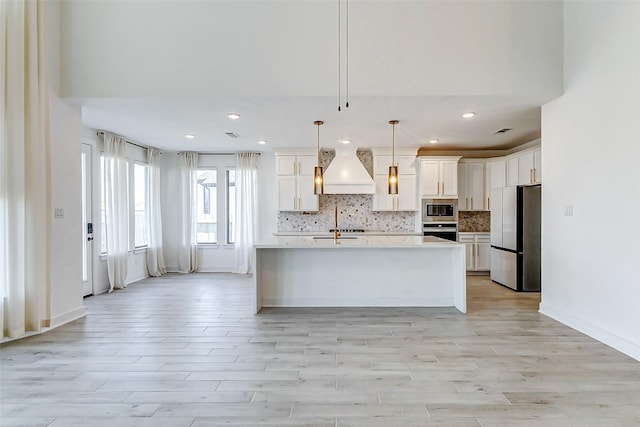 kitchen with tasteful backsplash, custom range hood, stainless steel appliances, light countertops, and white cabinetry