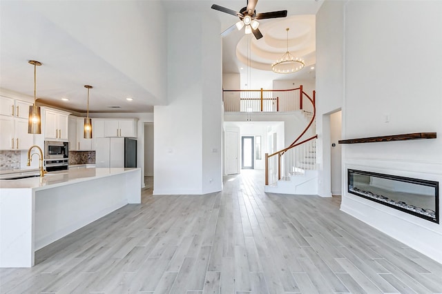 kitchen featuring light countertops, appliances with stainless steel finishes, light wood-type flooring, and a glass covered fireplace