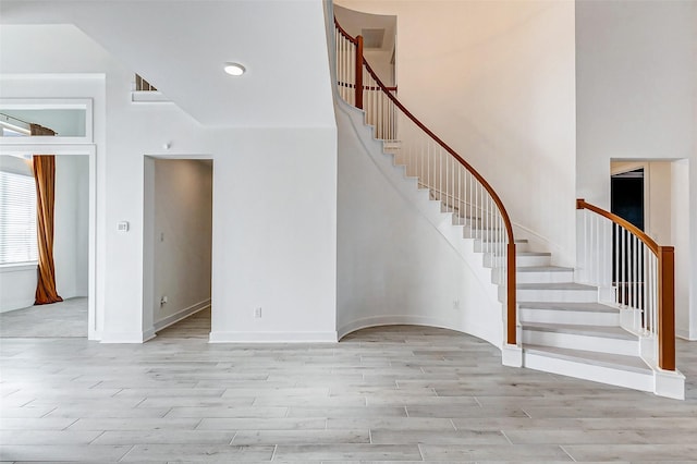 interior space featuring a high ceiling, baseboards, and wood finished floors