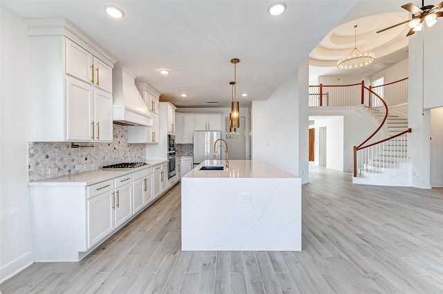 kitchen featuring light wood-style floors, custom exhaust hood, backsplash, and gas cooktop