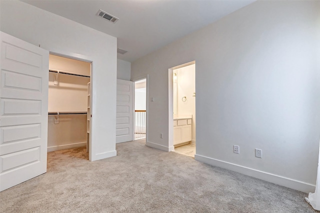 unfurnished bedroom featuring a walk in closet, carpet, a closet, visible vents, and baseboards