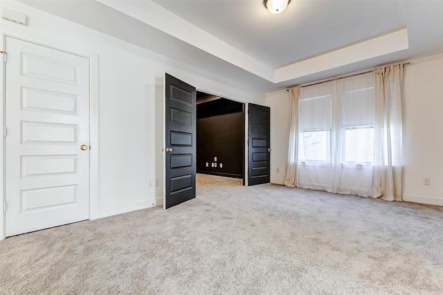 unfurnished bedroom with baseboards, a raised ceiling, and carpet flooring