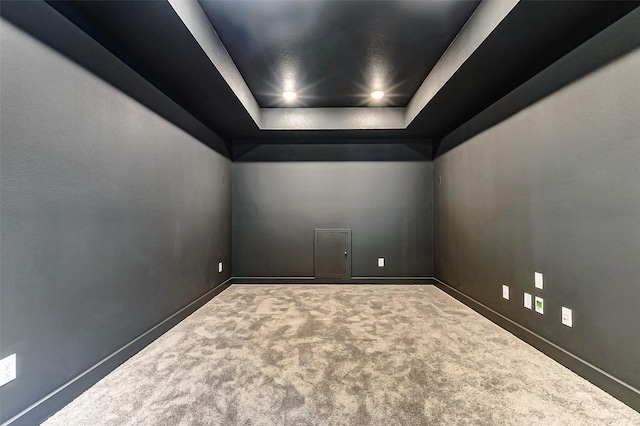 carpeted empty room with a tray ceiling and baseboards