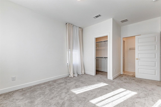 unfurnished bedroom featuring baseboards, visible vents, a walk in closet, and carpet flooring