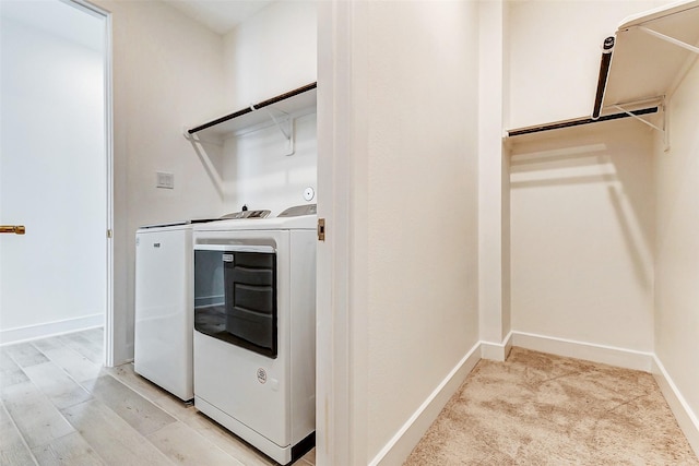 washroom with laundry area, light wood-style floors, washing machine and dryer, and baseboards